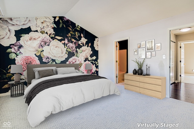 bedroom featuring ensuite bathroom, wood-type flooring, and lofted ceiling