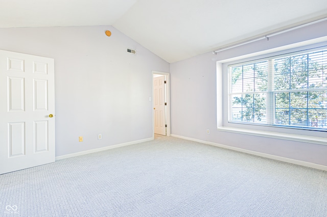 carpeted empty room featuring vaulted ceiling