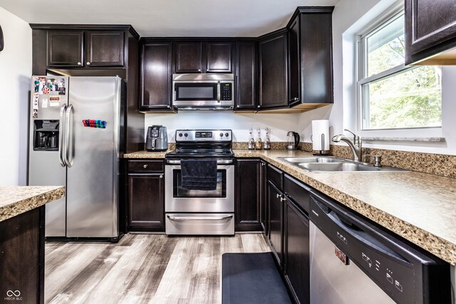 kitchen featuring light wood-type flooring, stainless steel appliances, dark brown cabinetry, and sink