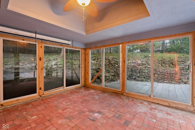 unfurnished sunroom with ceiling fan and a raised ceiling