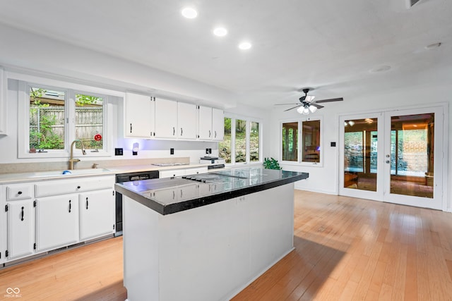 kitchen featuring light wood-type flooring, dishwasher, a center island, sink, and white cabinetry