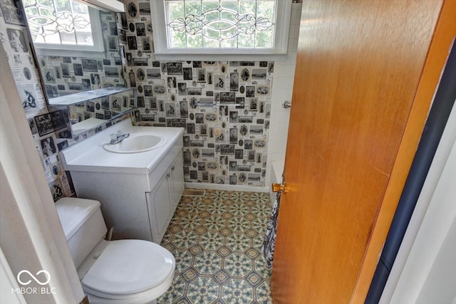 bathroom with a shower, vanity, toilet, and plenty of natural light