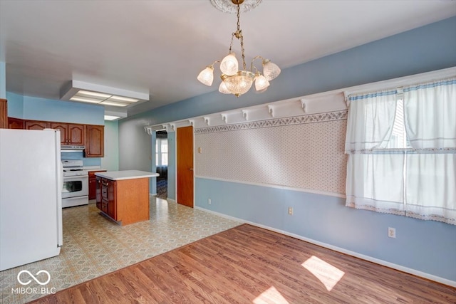 kitchen with hanging light fixtures, white appliances, a kitchen island, light wood-type flooring, and an inviting chandelier