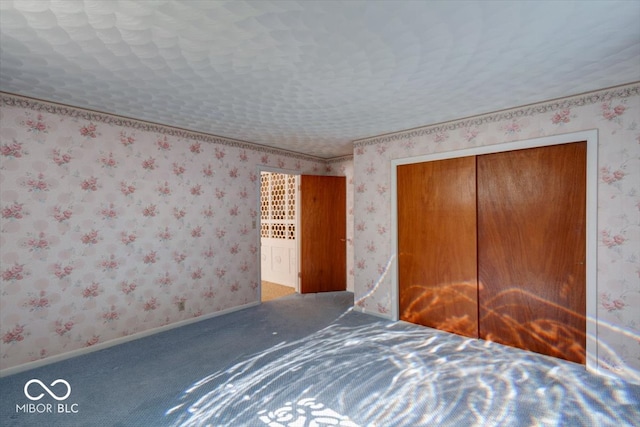 unfurnished bedroom with a textured ceiling, a closet, and carpet flooring