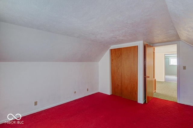 additional living space featuring vaulted ceiling, a textured ceiling, and carpet flooring