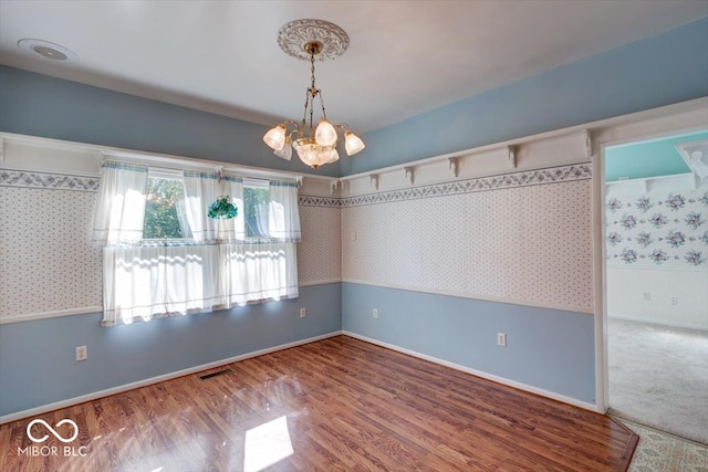 unfurnished room with a notable chandelier and hardwood / wood-style floors