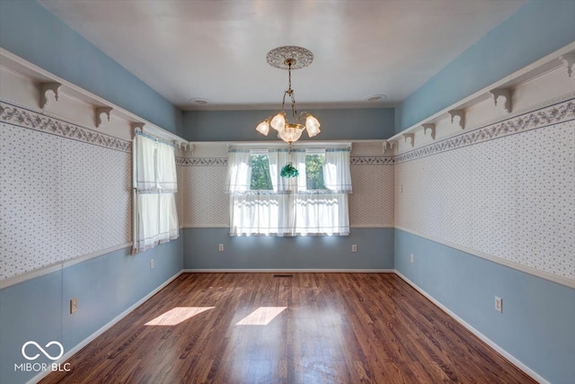 unfurnished dining area featuring an inviting chandelier and dark wood-type flooring