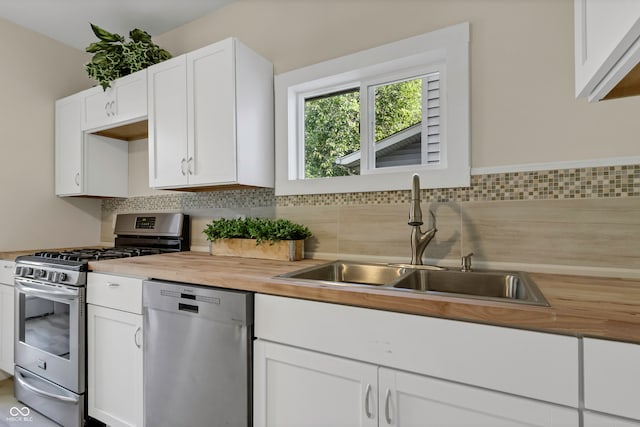 kitchen with white cabinetry, tasteful backsplash, butcher block countertops, stainless steel appliances, and sink