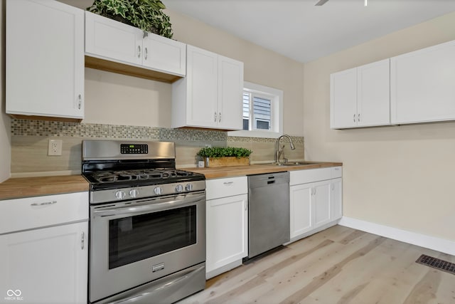 kitchen featuring stainless steel appliances, white cabinetry, tasteful backsplash, and sink