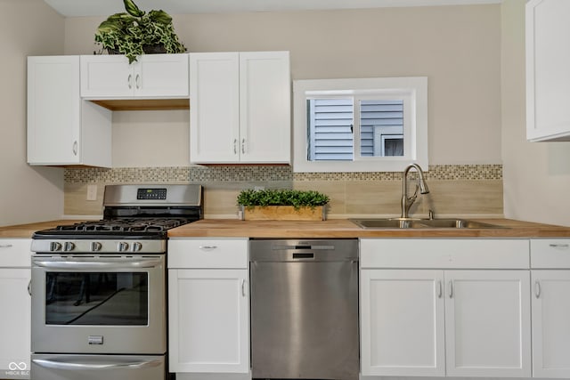 kitchen with white cabinetry, appliances with stainless steel finishes, wood counters, and sink