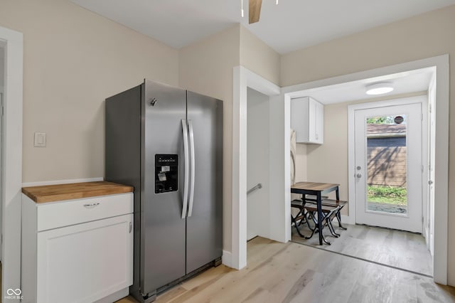 kitchen with stainless steel refrigerator with ice dispenser, light hardwood / wood-style floors, butcher block counters, and white cabinets