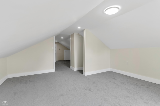 additional living space featuring light colored carpet and lofted ceiling