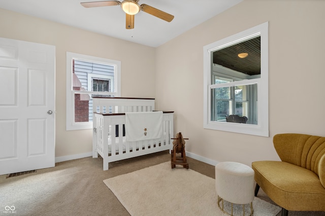 bedroom featuring carpet, ceiling fan, and a crib