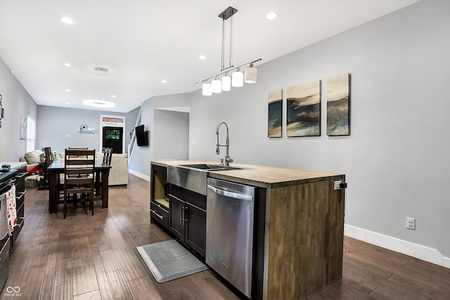 kitchen featuring dark wood-style flooring, a kitchen island with sink, butcher block countertops, dishwasher, and baseboards