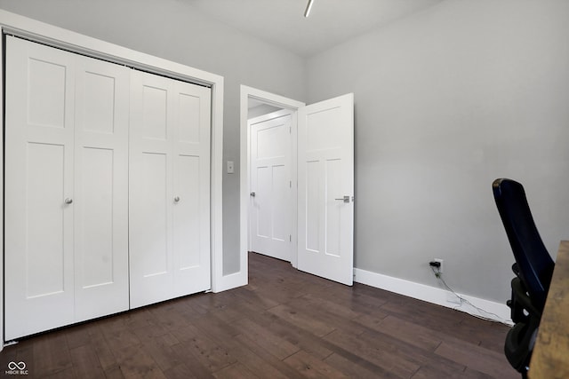 unfurnished bedroom featuring baseboards, dark wood finished floors, and a closet