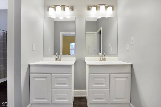 full bathroom with two vanities, a sink, and baseboards