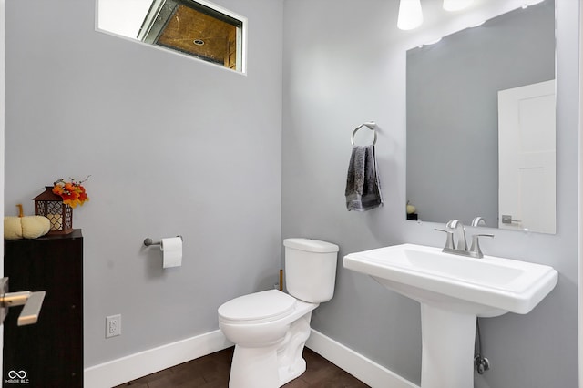 half bathroom with a sink, wood finished floors, toilet, and baseboards