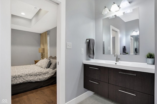 ensuite bathroom featuring wood finished floors, vanity, baseboards, and ensuite bathroom