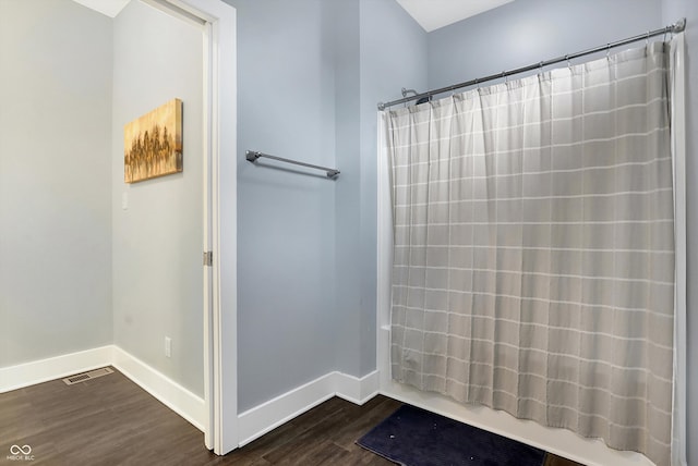 full bathroom with shower / bath combo, visible vents, baseboards, and wood finished floors