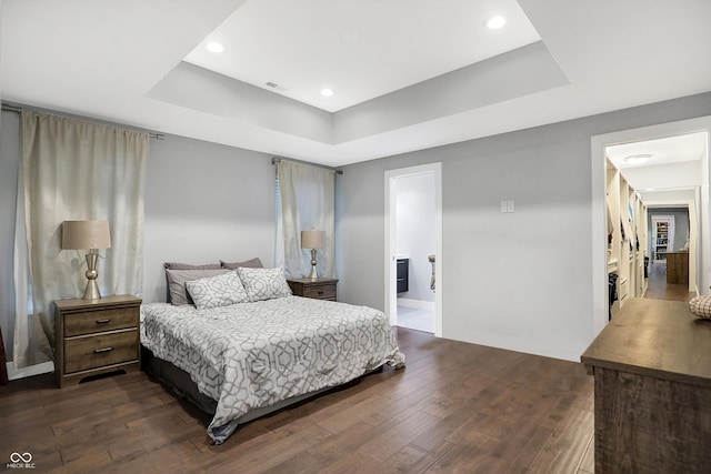 bedroom with a tray ceiling, visible vents, dark wood finished floors, and recessed lighting