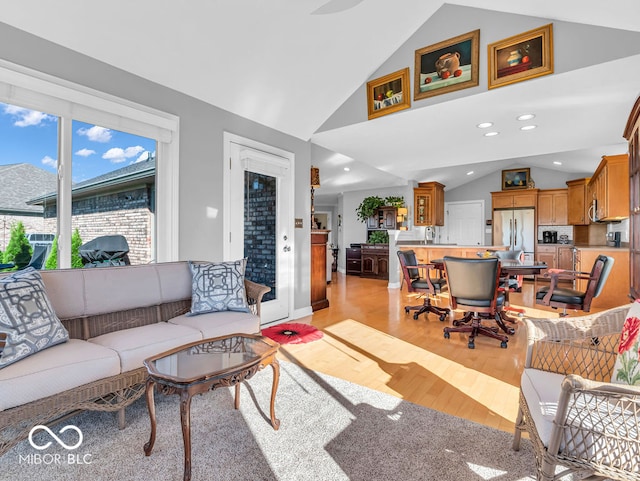 living room featuring vaulted ceiling, sink, and light hardwood / wood-style flooring