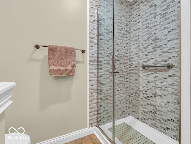 bathroom featuring tile patterned flooring, a shower with door, and toilet