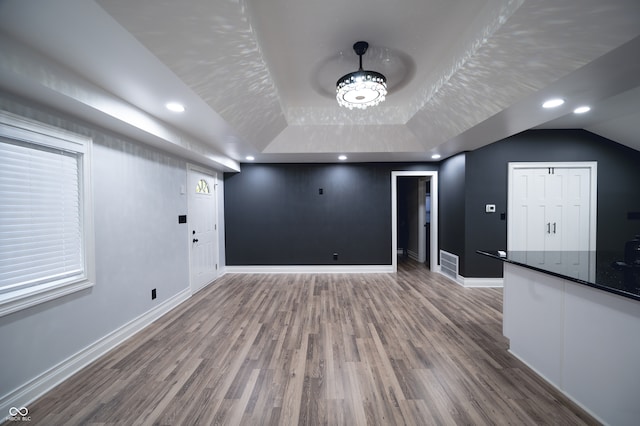 unfurnished living room featuring hardwood / wood-style flooring and a raised ceiling