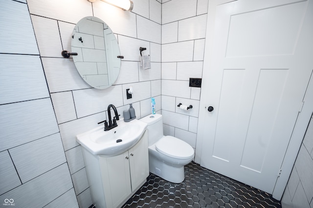 bathroom with tile walls, vanity, and toilet