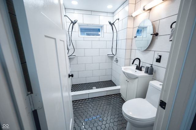 bathroom featuring tile walls, vanity, a tile shower, tile patterned flooring, and toilet