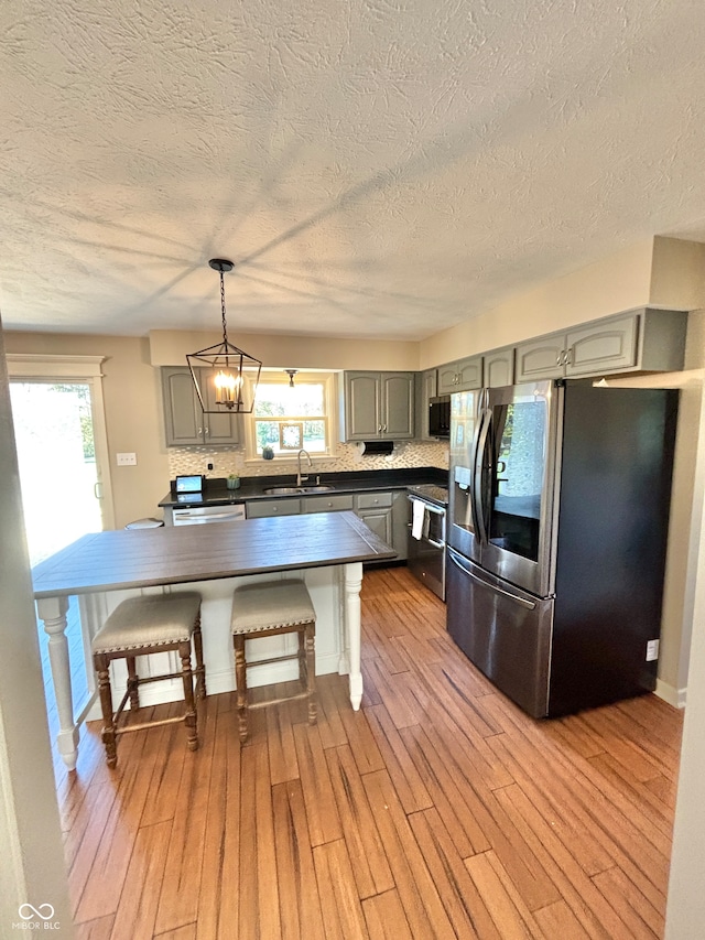 kitchen featuring gray cabinetry, pendant lighting, a center island, appliances with stainless steel finishes, and light hardwood / wood-style floors