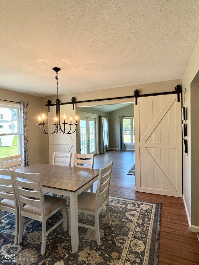 dining area with a barn door, dark hardwood / wood-style flooring, and a wealth of natural light