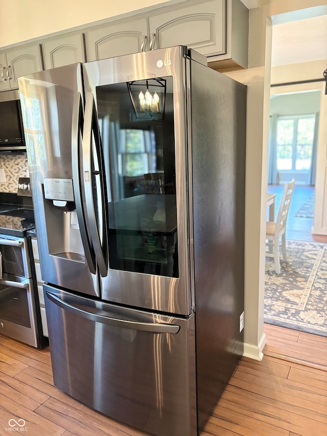 kitchen with gray cabinets, light hardwood / wood-style flooring, and appliances with stainless steel finishes