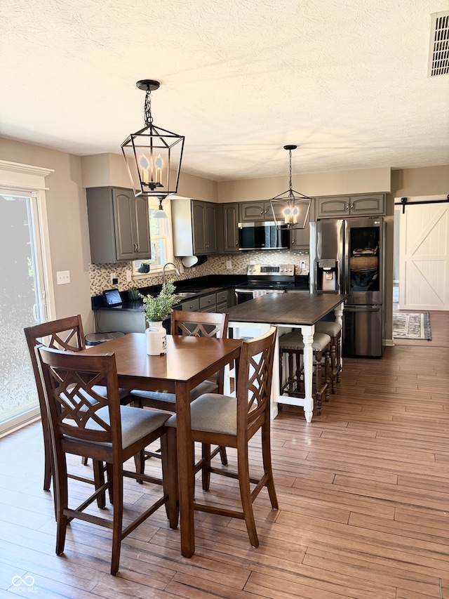 dining room featuring a chandelier, dark hardwood / wood-style flooring, a barn door, and a wealth of natural light