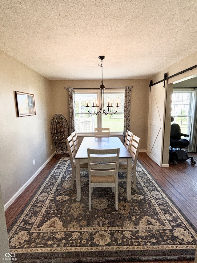 dining area featuring a barn door, dark hardwood / wood-style floors, an inviting chandelier, and a healthy amount of sunlight