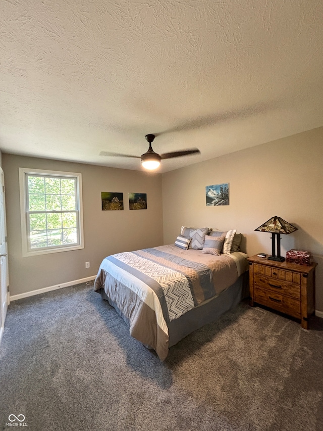 bedroom featuring dark colored carpet, ceiling fan, and a textured ceiling