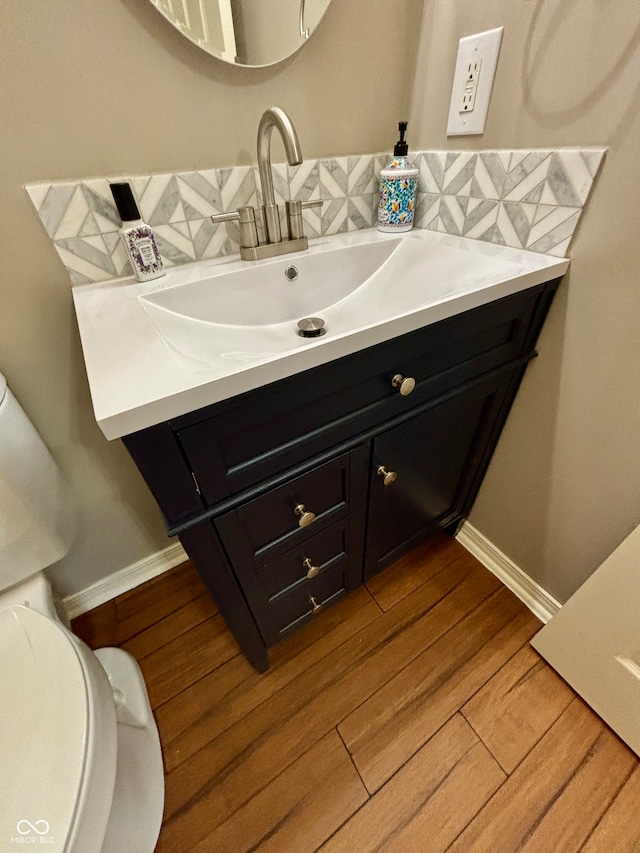 bathroom with wood-type flooring, vanity, tasteful backsplash, and toilet