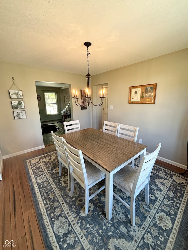 dining space featuring a textured ceiling, dark wood-type flooring, and an inviting chandelier