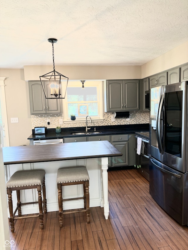 kitchen featuring stainless steel refrigerator with ice dispenser, dark hardwood / wood-style flooring, a breakfast bar, sink, and gray cabinets