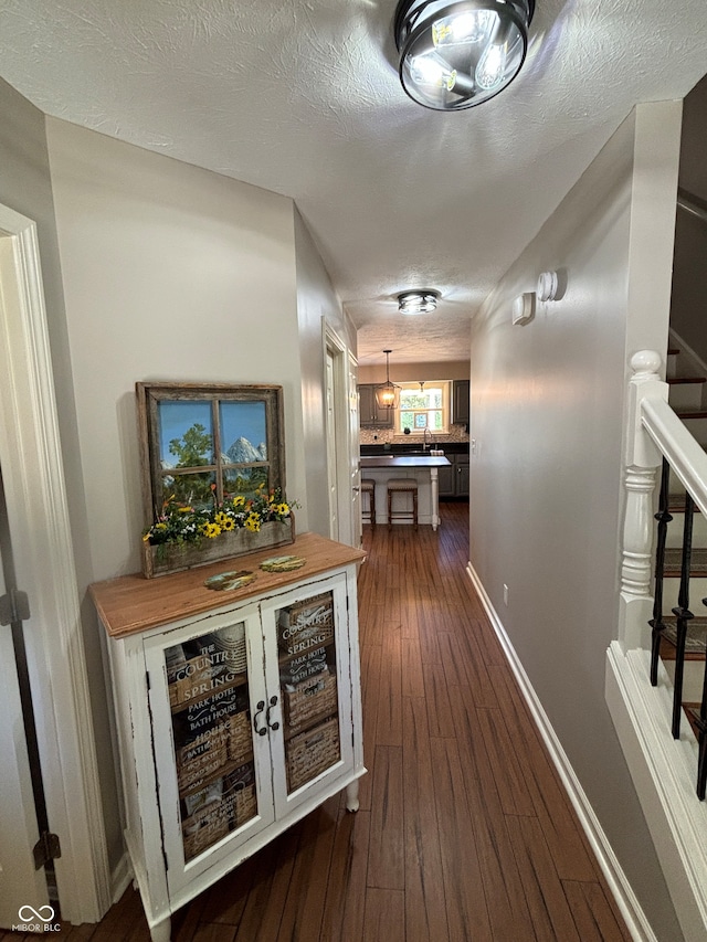 corridor with a textured ceiling and dark hardwood / wood-style floors