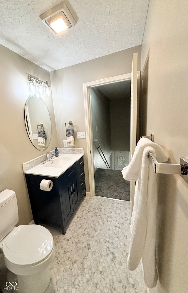 bathroom with vanity, toilet, and a textured ceiling