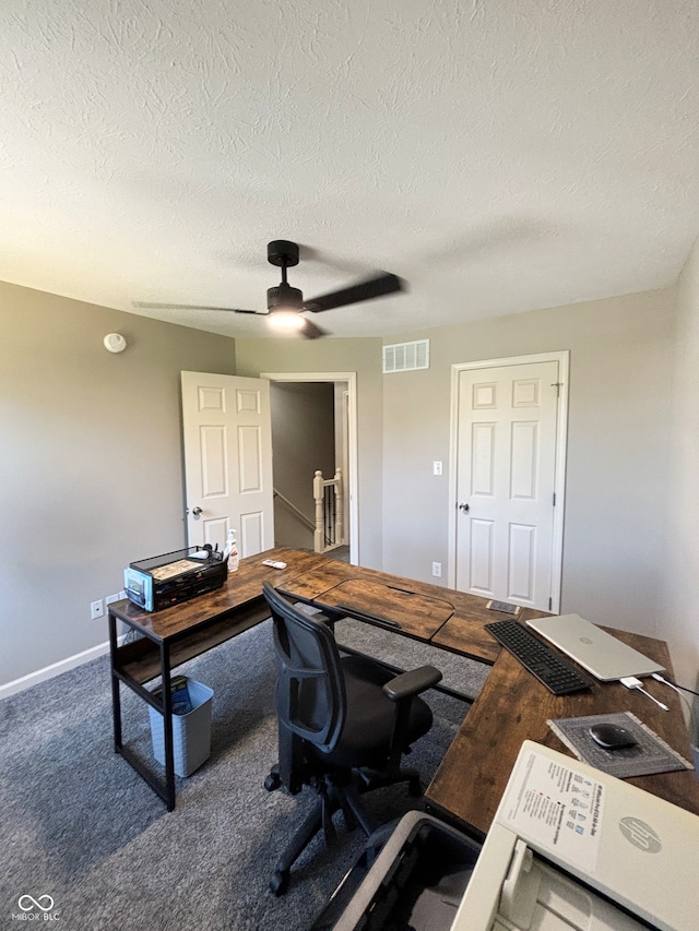 carpeted home office with ceiling fan and a textured ceiling