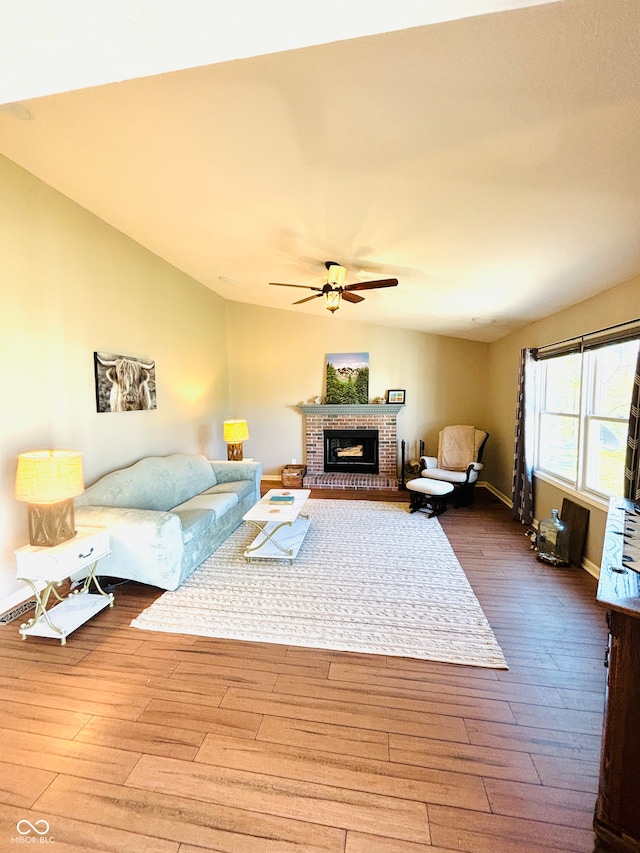 living room featuring ceiling fan, a fireplace, wood-type flooring, and lofted ceiling