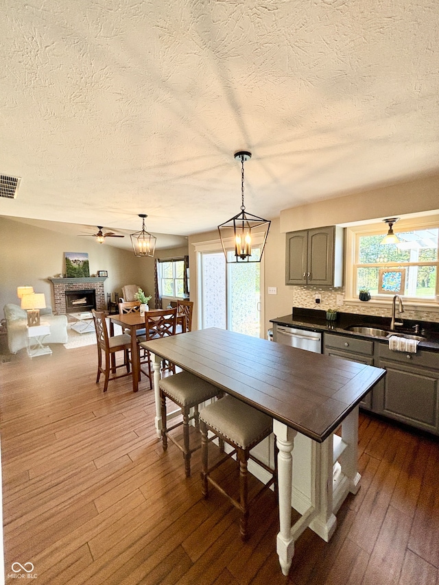 kitchen featuring pendant lighting, ceiling fan with notable chandelier, dark hardwood / wood-style flooring, and sink