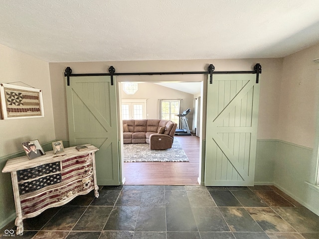 doorway with a textured ceiling, a barn door, and dark hardwood / wood-style floors