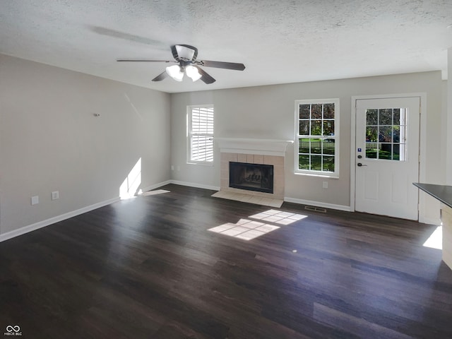 unfurnished living room featuring a tiled fireplace, dark hardwood / wood-style floors, and a wealth of natural light