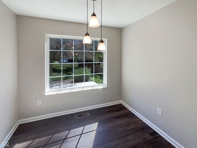 unfurnished dining area with a textured ceiling and dark hardwood / wood-style flooring