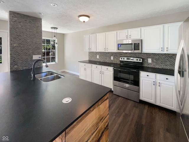 kitchen featuring white cabinetry, stainless steel appliances, decorative light fixtures, dark hardwood / wood-style floors, and sink