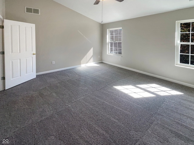 unfurnished room with dark carpet, vaulted ceiling, and ceiling fan