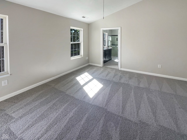 carpeted empty room featuring lofted ceiling