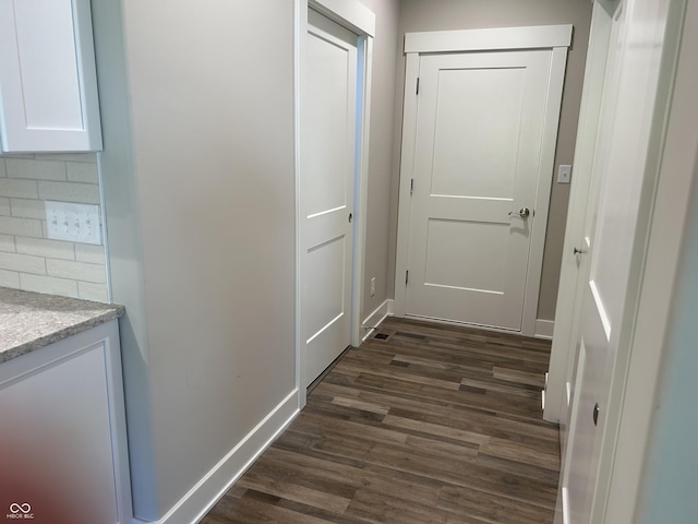 hall with dark wood-type flooring and baseboards